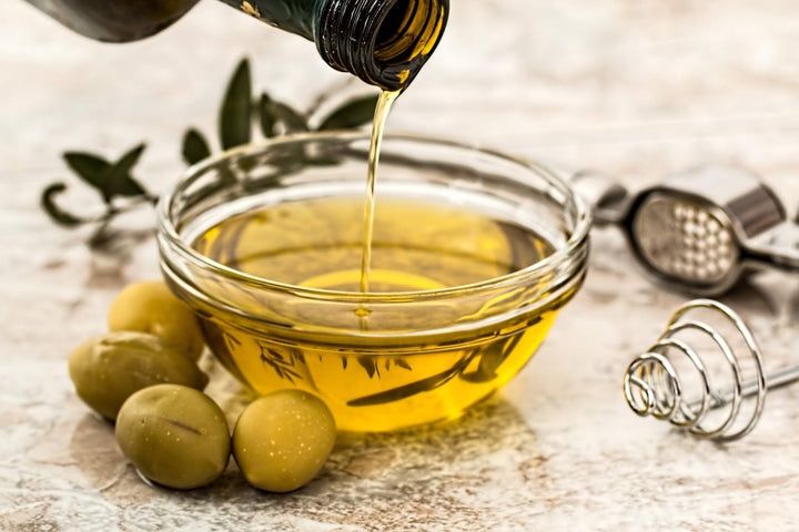 Kleine Flasche gefüllt mit Olivenöl und Thymian; Holzkorken schließt die Falsche; ein paar Thymian-Blätter liegen um das Glasfläschchen herum